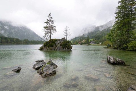 Hintersee near Ramsau, surrounded by forests and mountains under a cloudy rainy sky, fog,