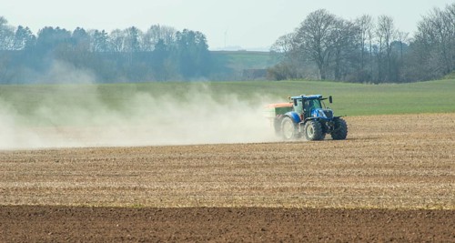 Spring farming, spreading fertilizer with tractor on field in Ystad municipality, Skåne county,