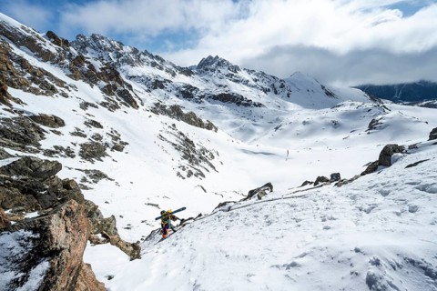 Mountaineer with skis climbing up a steep snow slope to the fork Porta d'Es-cha, ski tour Bündner