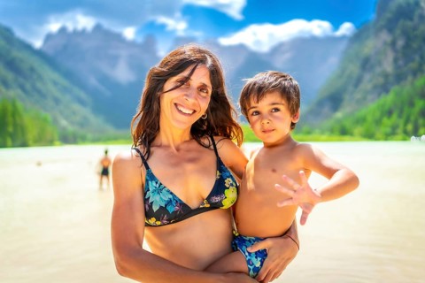 Mother holding her son while enjoying a swim in the beautiful lago di landro in the italian