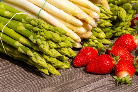 Green asparagus, white asparagus and fresh strawberries decorated on a rustic wooden table