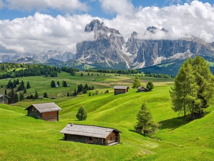 Spring on the Seiser Alm, alpine huts with Plattkofel and Langkofel, clouds, Dolomites, South Tyrol