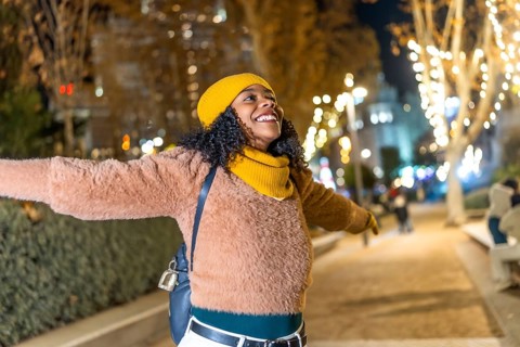 Young woman embracing the festive spirit of christmas lights while enjoying a winter evening in the