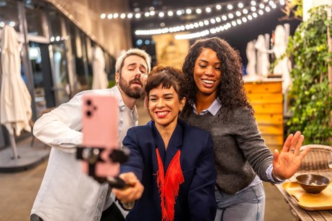 Diverse friends dancing recording tik tok video with smartphone at night party