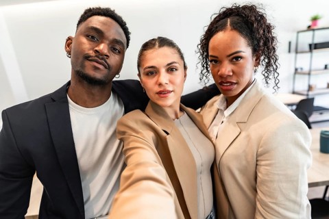 Three diverse business professionals are taking a selfie, showcasing their teamwork and positive