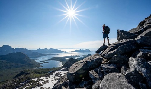 View of mountains and fjord landscape, mountaineer at the summit of Rundfjellet, Sun Star,