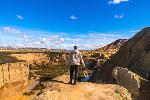 Tourist standing on cliff edge admiring the stunning landscape of bardenas reales desert in