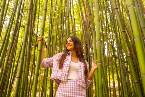 Young caucasian girl with a pink skirt in a bamboo forest. Enjoying the summer holidays in a