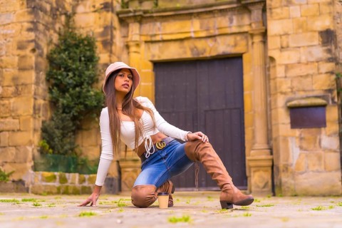 A young Latin woman with a white t-shirt, jeans and a hat enjoying the summer holidays, with a take