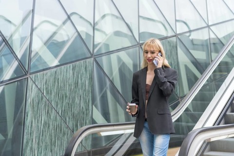 Entrepreneurial girl in business park in a modern building with escalator, young blonde in a suit
