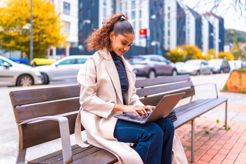 Side view photo with copy space of a beauty elegant african woman sitting on a city bench using