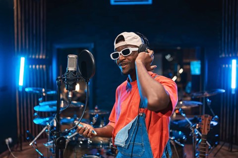 Talented musician wearing trendy clothes, holding smartphone and adjusting headphones while