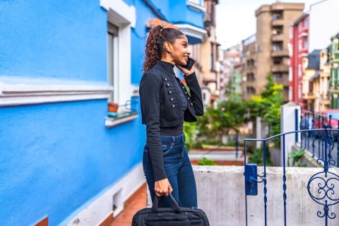 Side view photo of an african american casual businesswoman walking talking to the mobile among