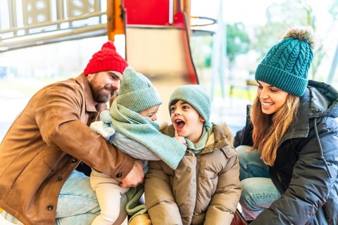 Family enjoying a winter day at the playground, bundled up in warm clothes and laughing together