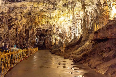Tourists visiting the magnificent postojna cave in slovenia, riding an electric train through
