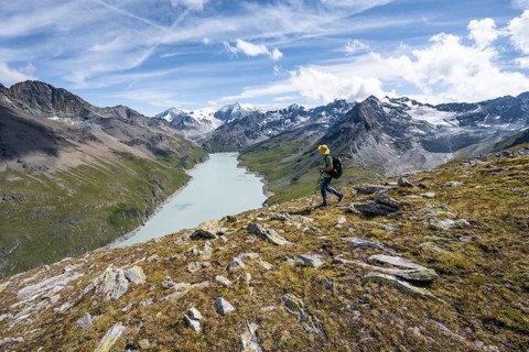 Mountaineer on the summit of Mont de la Blana, view of a blue mountain lake, Lac des Dix reservoir,