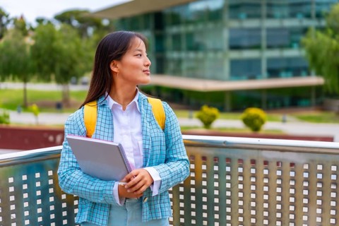 Three quarter length portrait of a beauty female chinese student looking away distracted standing