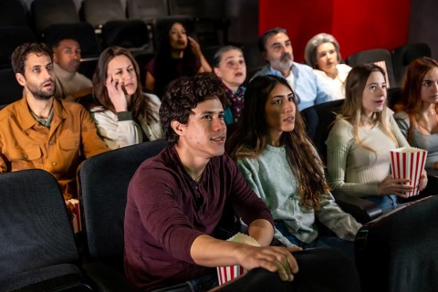 Captivated audience members of various ages and ethnicities experience a thrilling movie screening