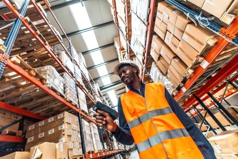 Low angle view of an african manual worker scanning packages to deliver in a warehouse
