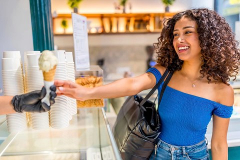 Side view of a happy latin beauty woman shopping ice cream cone at store