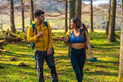 Hikers enjoying a healthy snack of apples while walking through a sunny forest during their outdoor