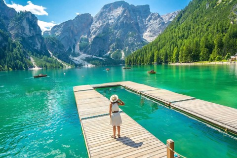 Tourist admiring the breathtaking landscape of lake braies, with its crystal clear turquoise waters