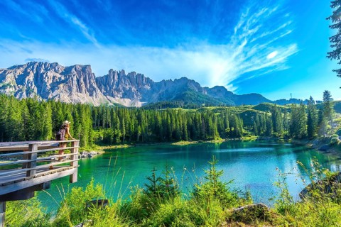 Female tourist admiring the stunning turquoise waters of lake carezza with the latemar mountain