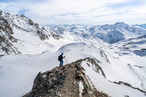 Mountain panorama with view of peaks of the Bernina group, mountaineer descending Piz Grialetsch in