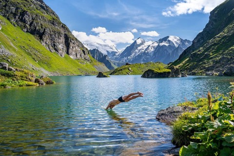 Man taking a header, cooling off while swimming in the mountain lake Lac de Louvie, behind the