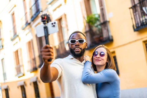 Multi-ethnic couple influencer vlogging from a travel destination standing in the city street