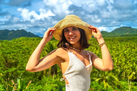 Young woman enjoying a sunny day in a coconut plantation in siargao island, philippines, holding