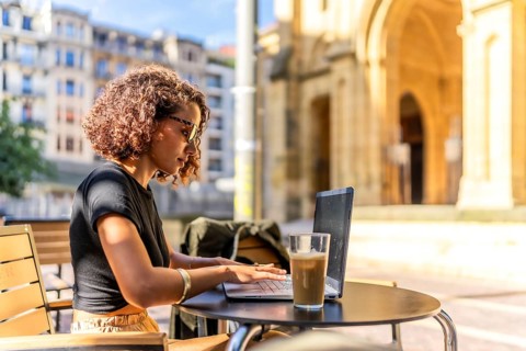 Arab young businesswoman working on remote in a sidewalk cafeteria in the main square of a city