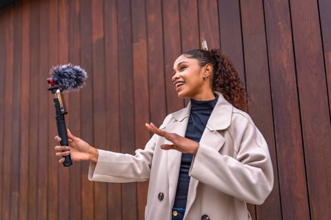 African american beauty woman vlogger talking to her audience streaming online next to wooden city