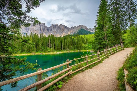 Emerald green water reflecting the majestic dolomites under a cloudy summer sky in south tyrol,