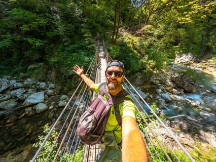 Hiker taking selfie while crossing hanging bridge over tolmin gorge in triglav national park,