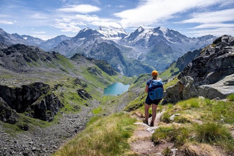 Hiker on hiking trail, mountain lake Lac de Louvie with glaciated summit of the Grand Combin, Val