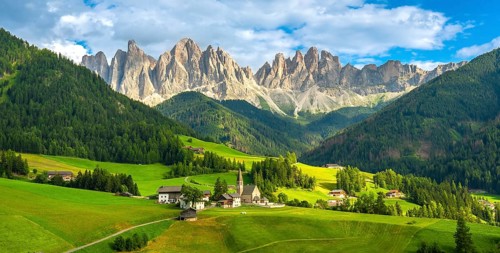 Green meadows, traditional houses, and the iconic santa maddalena church create a picturesque scene