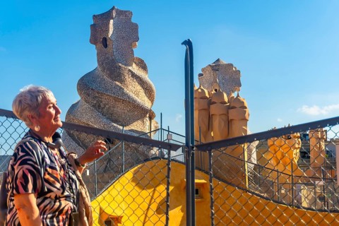 Senior tourist admiring the whimsical chimneys and vibrant architecture of casa mila, a unesco