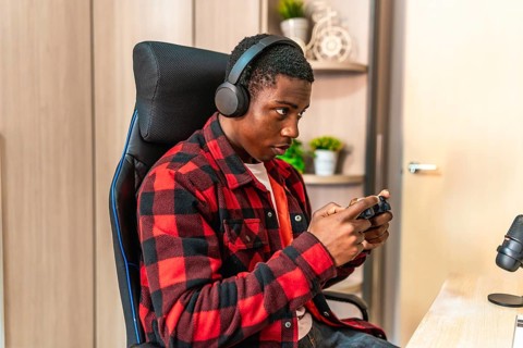 Young man engaging in video gaming and streaming online, wearing headphones and skillfully
