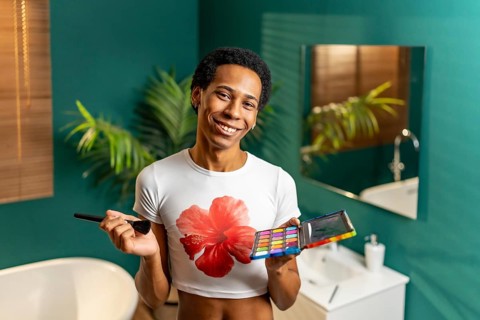 Portrait of a latin young gay smiling man making up at home