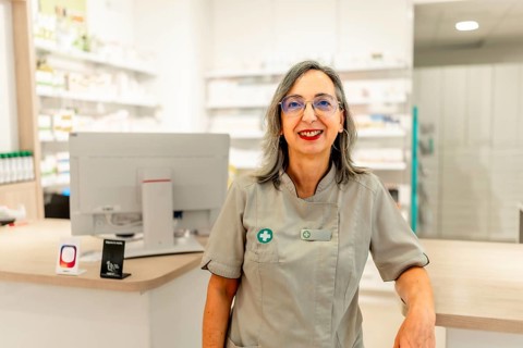 Portrait of a female pharmacist in uniform standing on the store
