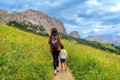 Mother and son walking on a path surrounded by lush green grass, enjoying the breathtaking view of