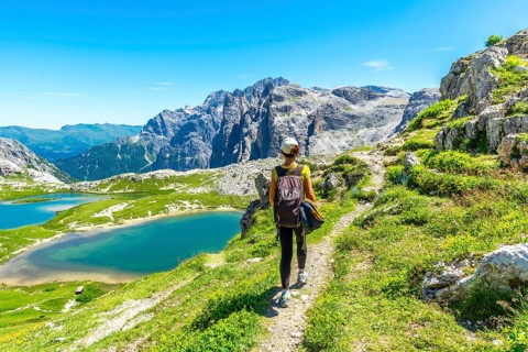 Tourist enjoying the scenic view of the tre cime di lavaredo and alpine lakes in the italian