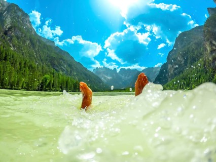 Feet of a tourist splashing in the turquoise water of lago di landro or durrensee lake, with the