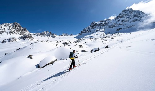 Ski tourers ascending through picturesque snow-covered mountain landscape with Piz Kesch summit,