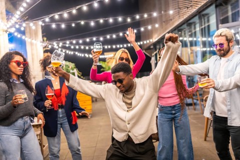 African cool man dancing next to multi-ethnic friends at outdoors party at night