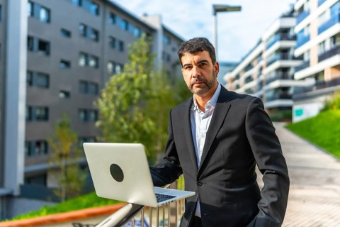 Portrait of a mature adult caucasian elegant and confident businessman using laptop standing in the