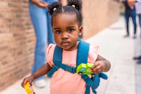 Close-up of an african cute schoolgirl carrying card toys in the street