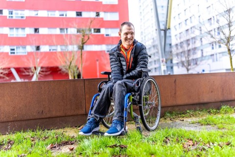 Young man with disability smiling in his wheelchair enjoying a day out in an urban park, promoting