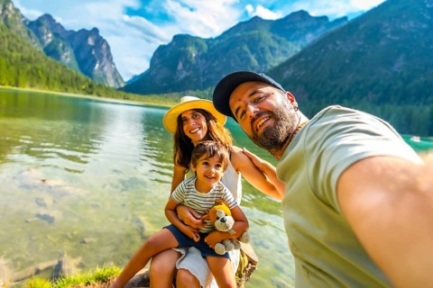 Tourists enjoying summer holidays by a picturesque alpine lake, capturing joyful moments with their